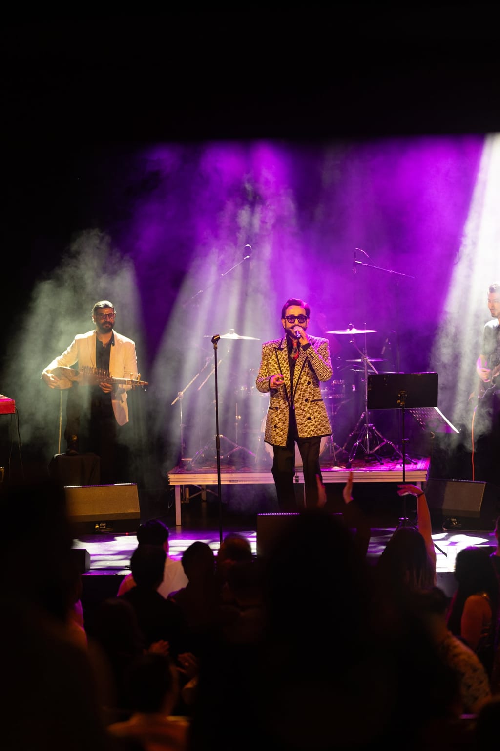 Habib Qaderi performing live on stage with his band, bathed in purple and blue light